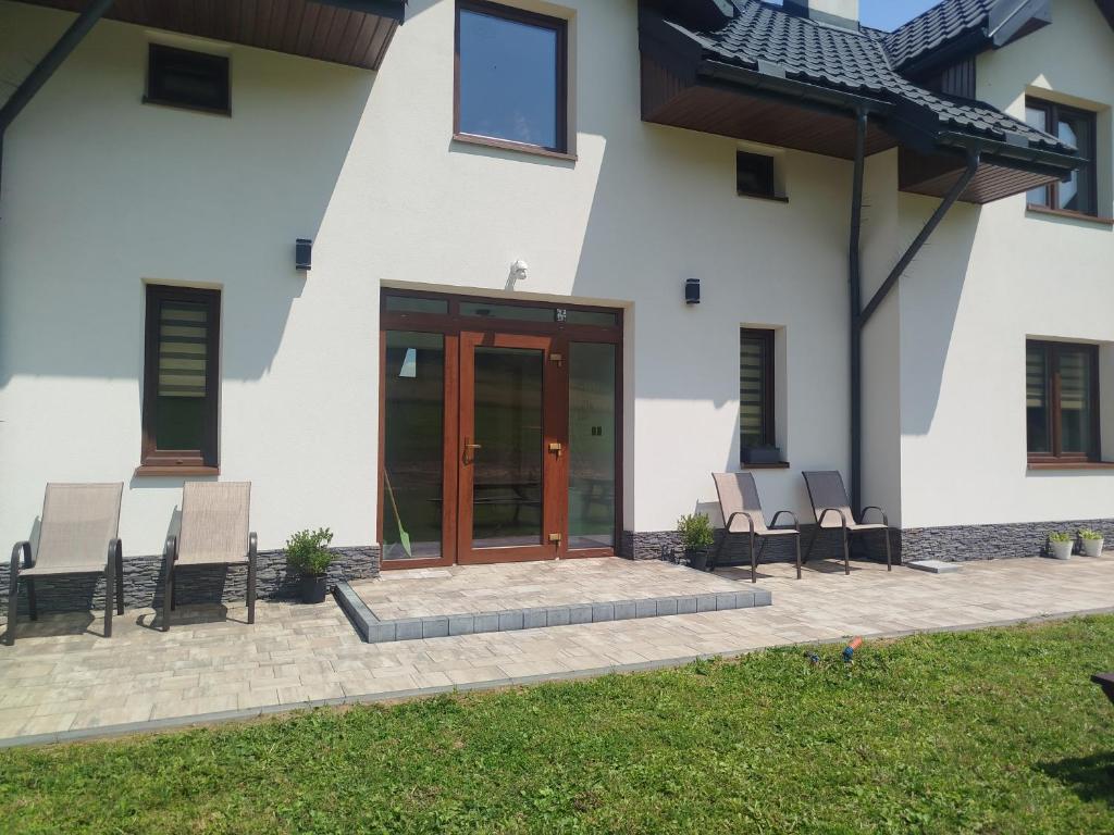 a house with two chairs and a glass door at Biała Ostoja 517-539-965 in Berezka