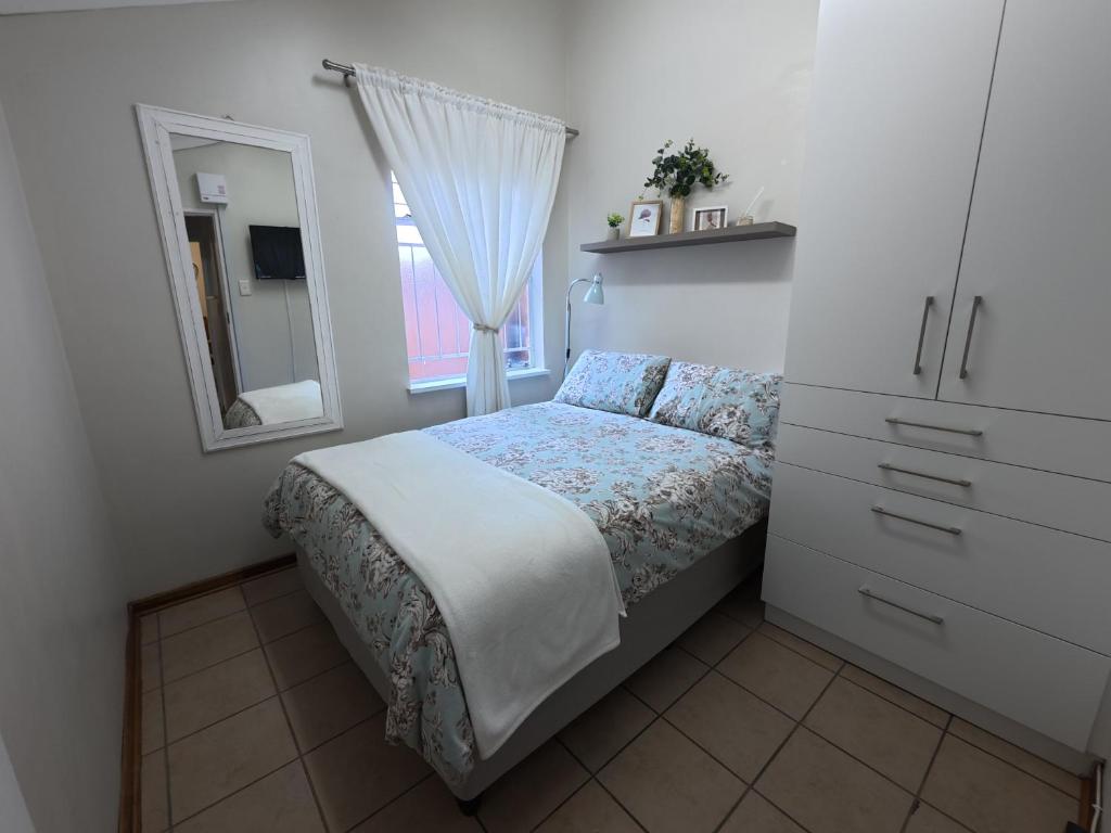 a small bedroom with a bed and a mirror at Glendale Cottage in Bloemfontein