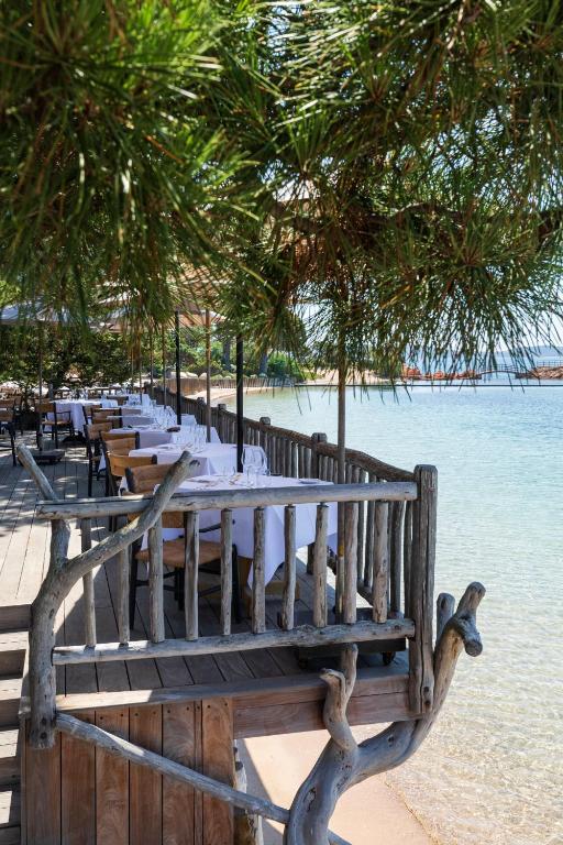 a long row of tables with white plates on the beach at Grand Hôtel De Cala Rossa & Spa Nucca in Porto-Vecchio