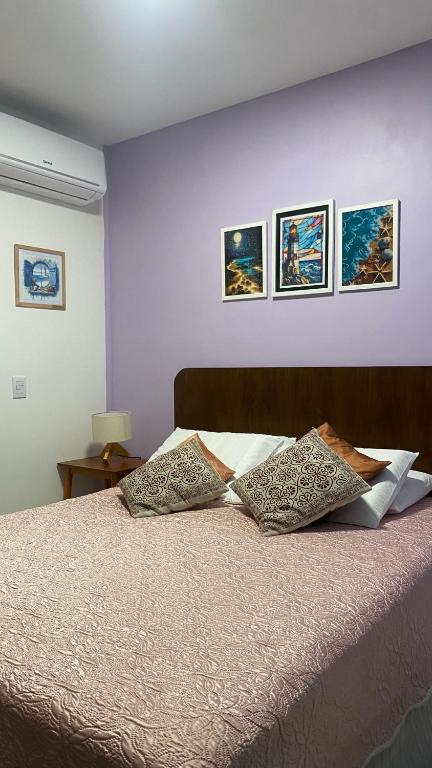 a bedroom with a bed with three pictures on the wall at Flat em muro alto in Ipojuca
