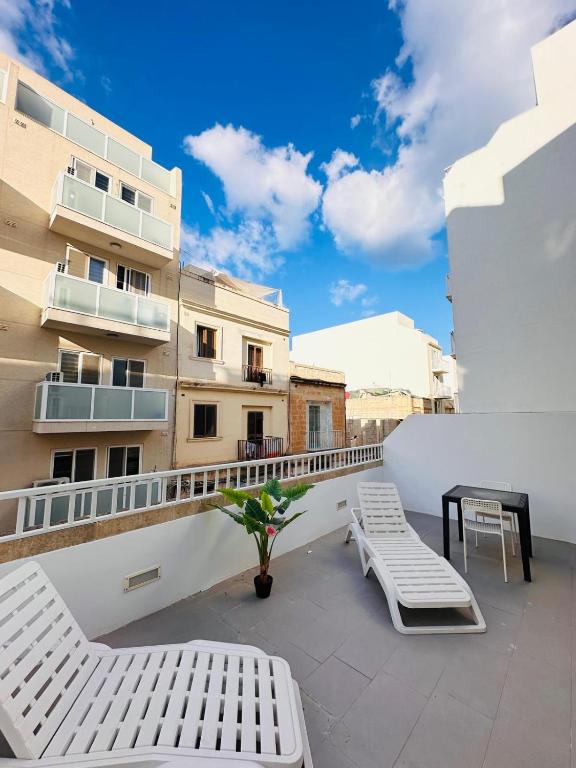 a balcony with two white benches and a building at Maltese House Gzira Central in Il-Gżira