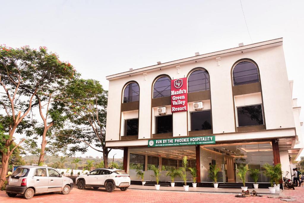 two cars parked in front of a building at Mandu's Green Valley Resort in Māndu