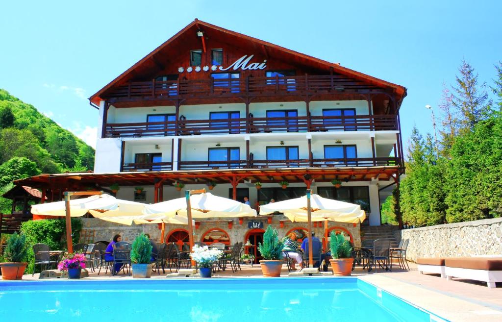 a hotel with a swimming pool in front of a building at Pensiunea Mai in Răşinari