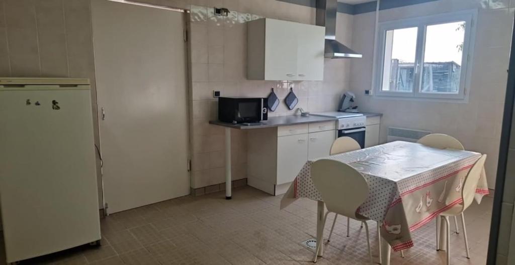 a kitchen with a table and chairs and a kitchen with a window at L'escapade in Rétaud