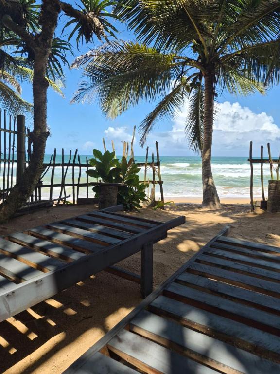 a bench on a beach with palm trees and the ocean at NATIVE SOULS Beach Hotel in Induruwa