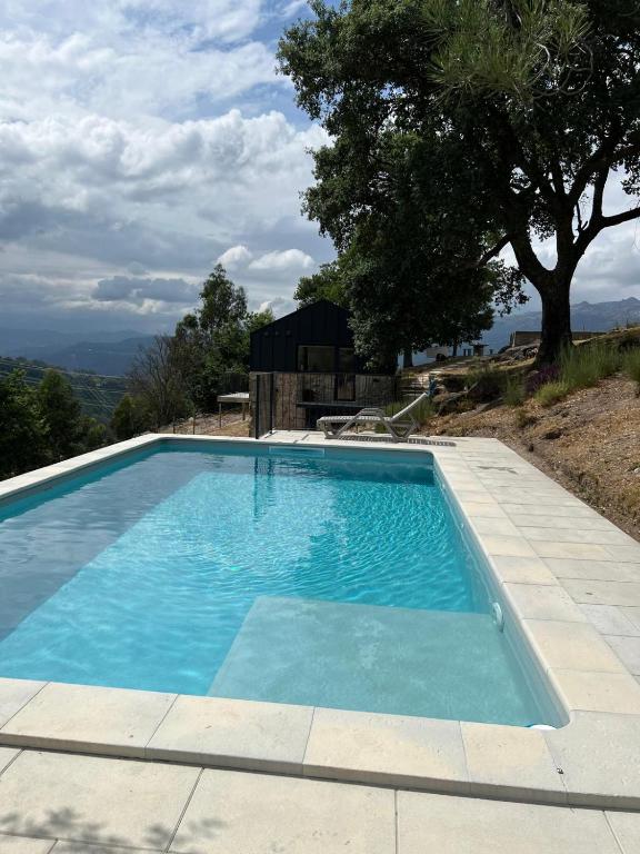 a blue swimming pool with a tree in the background at Refúgio do Saltadouro - Entre o Gerês e a Cabreira in Ruivãis