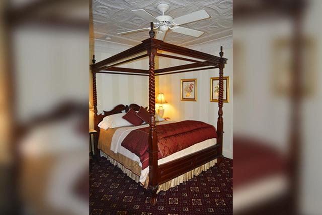 a bedroom with a canopy bed with a ceiling at Cornerstone Victorian Bed and Breakfast in Warrensburg
