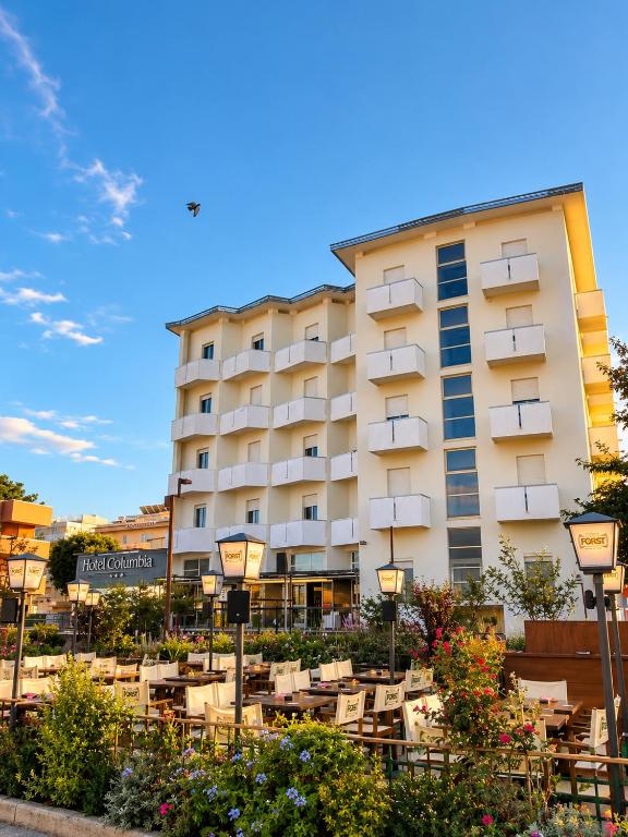 a hotel with tables and chairs in front of it at Hotel Columbia Frontemare in Rimini