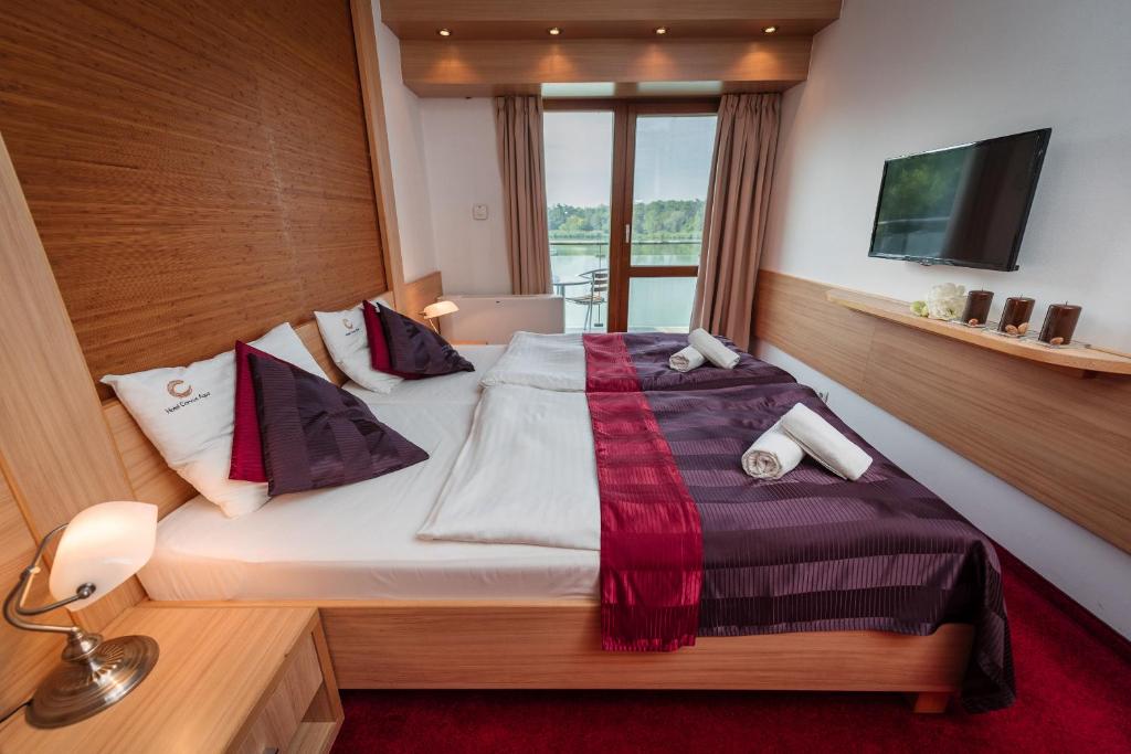 a bedroom with a large bed with a laptop on it at Hotel Corvus Aqua in Orosháza
