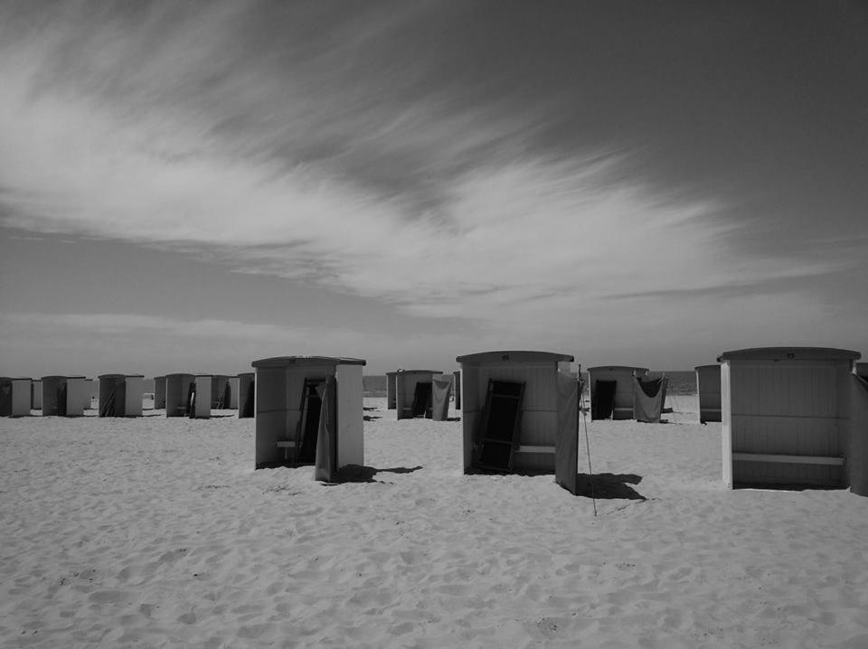 una fila de cabañas de playa en una playa de arena en B&B Mol, en Katwijk aan Zee