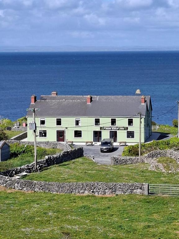 a white building with a car parked in front of the ocean at Tigh Fitz Apartments - Inis Mór, Aran Island in Inis Mor