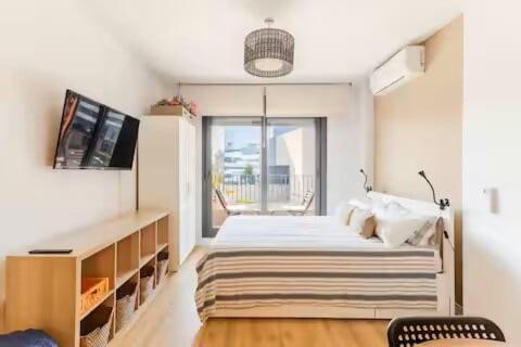 a white bedroom with a bed and a television at Studio Home Madrid in San Sebastián de los Reyes