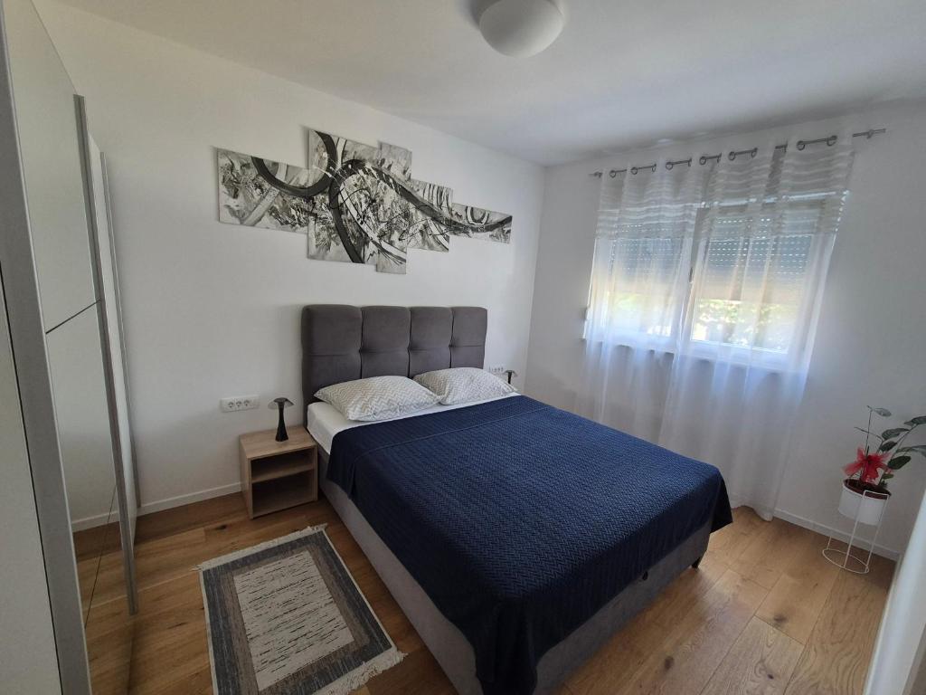 a bedroom with a blue bed and a window at Apartman Malomi in Solin