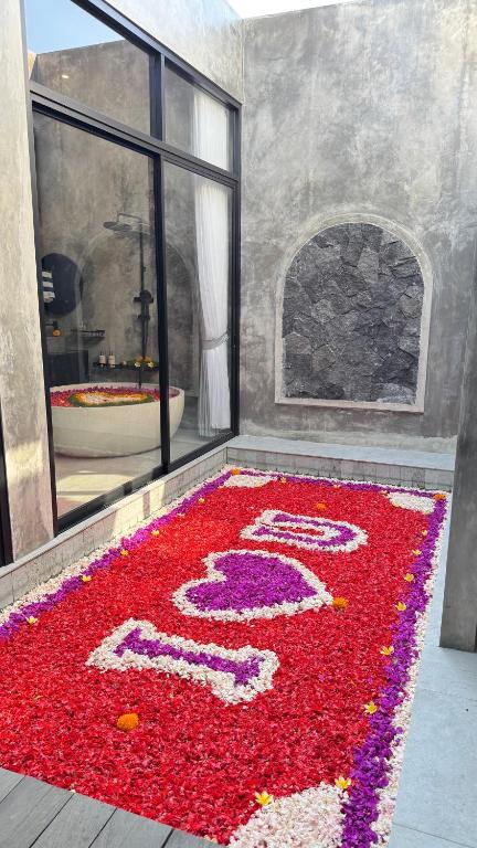a room with a number rug with red flowers at Nauti Villa in Ubud