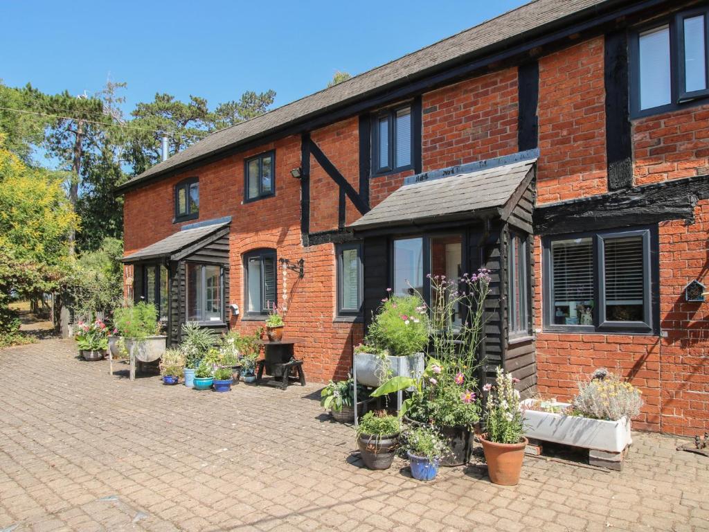 a brick building with potted plants in front of it at Apple Bough Cottage in Hereford
