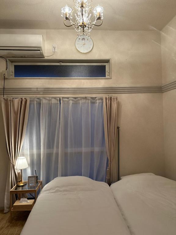 a bedroom with two beds and a chandelier at Guest House "Ro"Hieda B101 in Shimonoseki