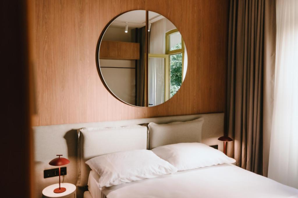 a bedroom with a white bed and a mirror at Meidan Heritage Suites Tbilisi in Tbilisi City