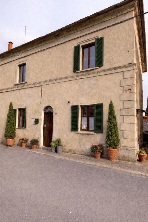 a building with green shuttered windows and potted plants at Aperto Tuscany apartment in Torrenieri