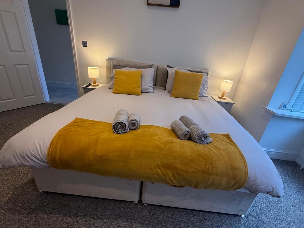 a bedroom with a large white bed with yellow pillows at Spacious John York House & Parking in Doncaster