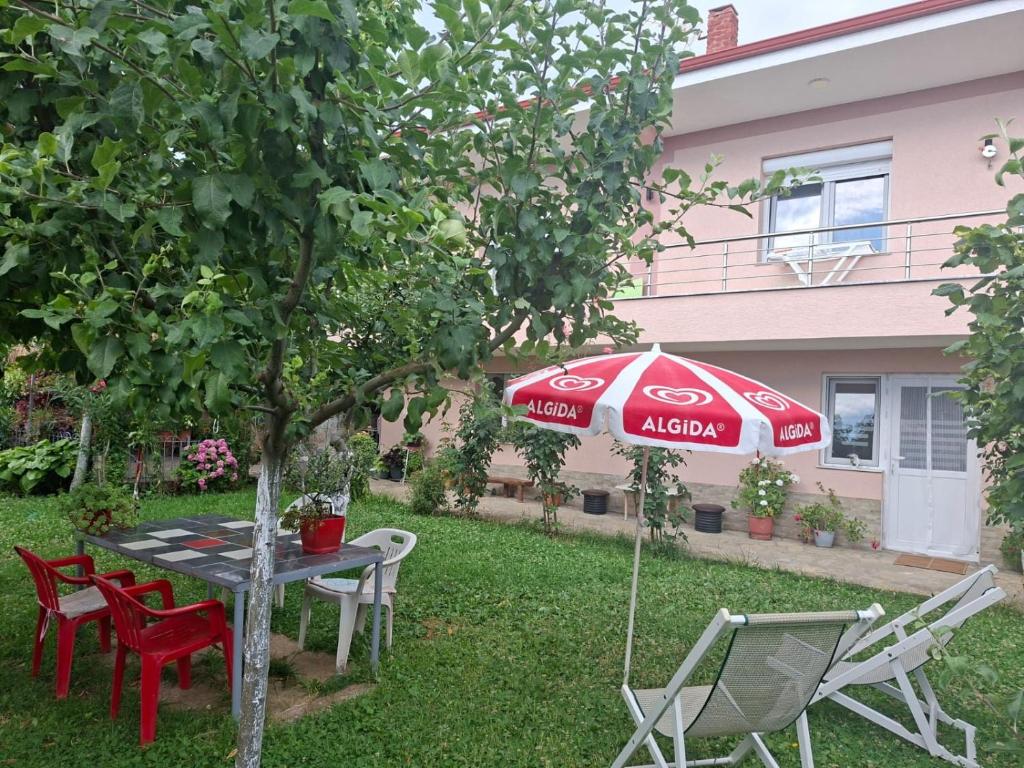 a table and chairs and an umbrella in a yard at Gardenhouse in Mëmëlisht