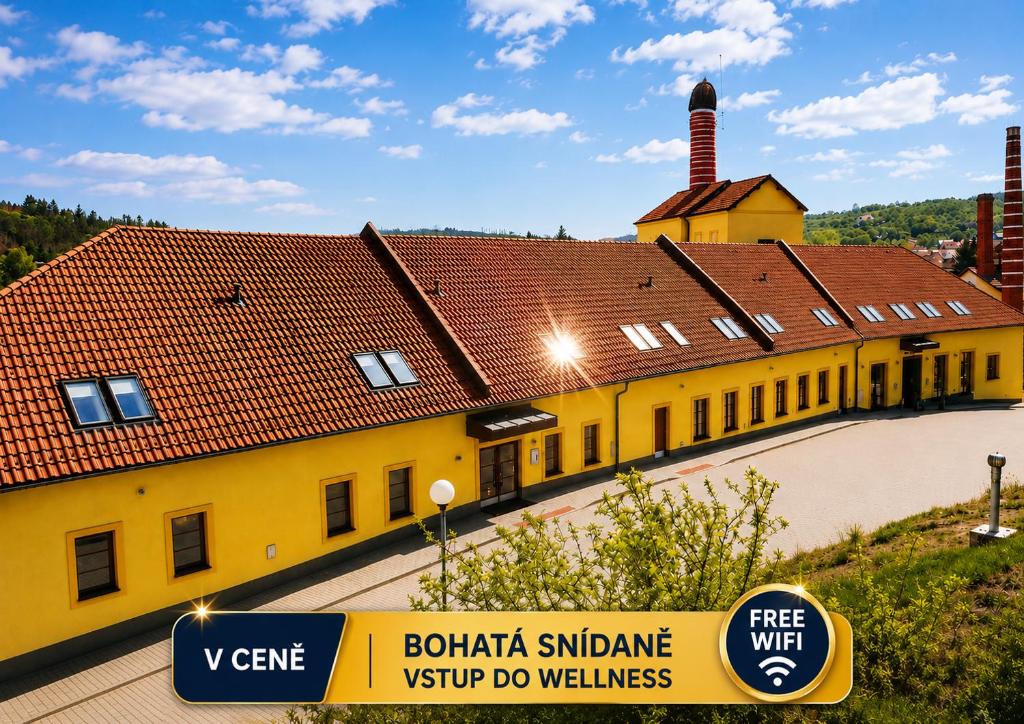 a large yellow building with a red roof at Hotel Sladovna in Černá Hora