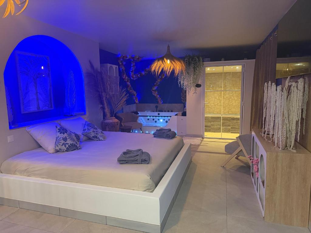 a bedroom with a large bed with purple lighting at gîte romantique in Etalondes-la-Pipe