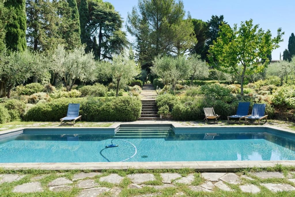 a swimming pool in a garden with two blue chairs at Villa Pian dei Giullari con Piscina in Florence
