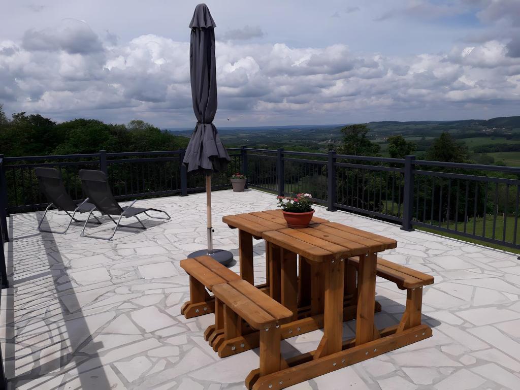 a patio with an umbrella and a table and chairs at Gîte la Roche du Gravillot in Château-Chinon