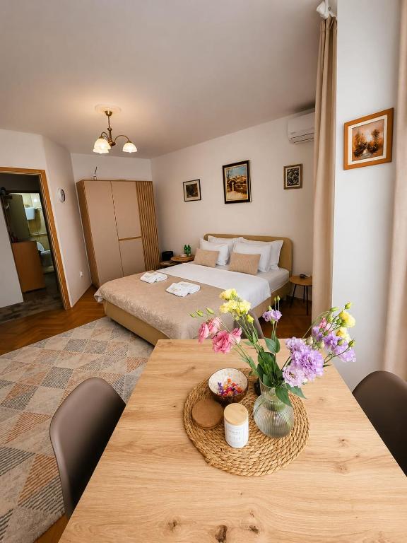 a bedroom with a bed and a table with flowers on it at Apartments Dragulji Kruševac Central Stay in Kruševac