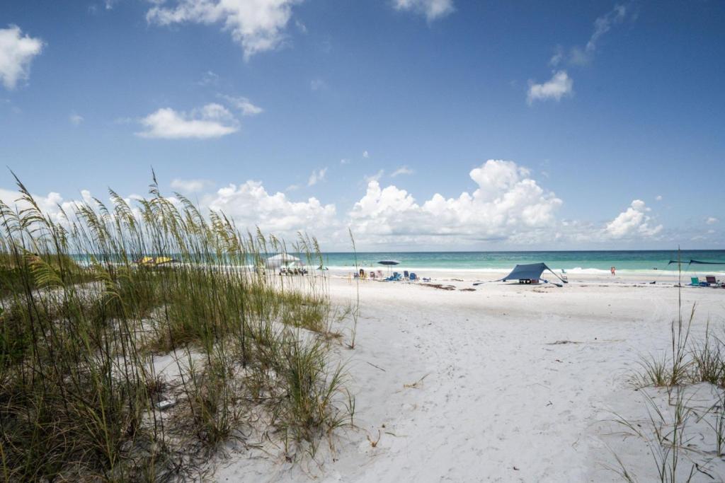 a beach with sand and grass and the ocean at Modern 3 Bedroom Beach Retreat with Private Balcony in Bradenton Beach