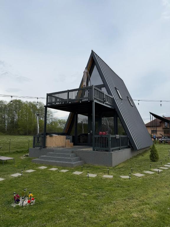 a house with a deck on top of a field at Cabana Ross-A in Poenari