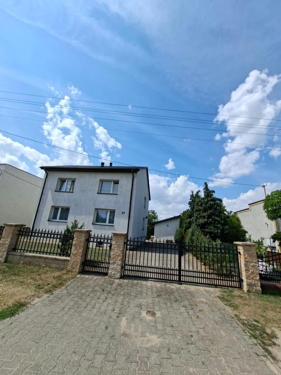 a white house with a black fence in front of it at Dom na Kościelnej in Ślesin