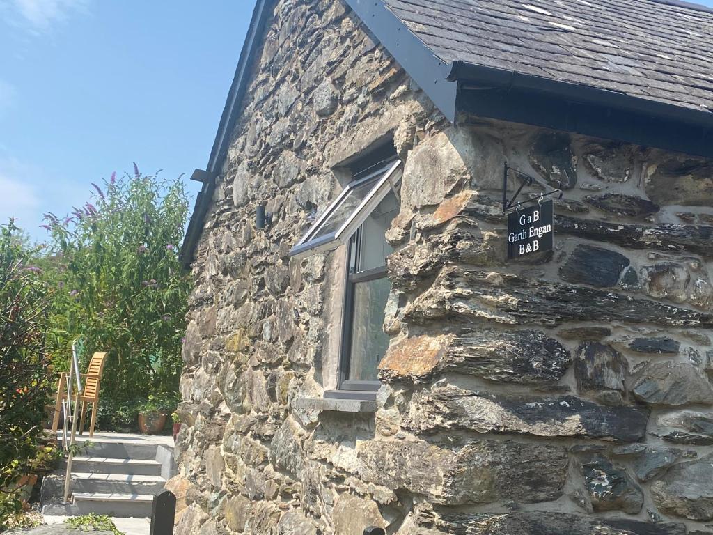 a stone house with a sign on the side of it at Garth Engan B&B with private lounge in Llanbedr