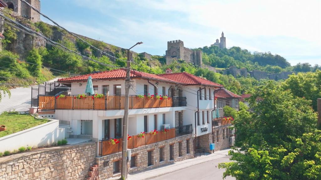 a house on a hill with a castle in the background at Tarnovka - Guest Rooms in Veliko Tŭrnovo