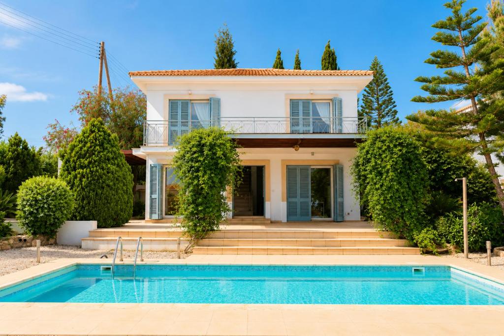 a villa with a swimming pool in front of a house at Villa Serenity in Neo Chorio