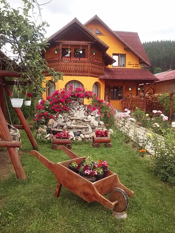 a garden in front of a house with flowers in a wheelbarrow at Casa Georgeta in Câmpulung Moldovenesc