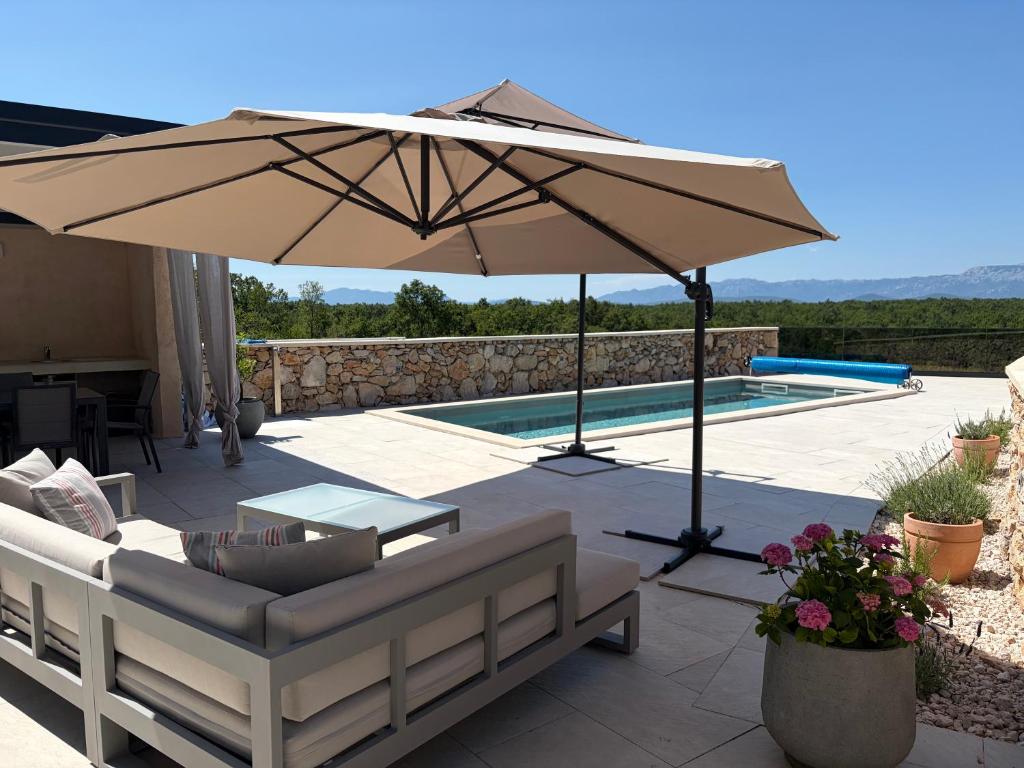 a patio with a table and an umbrella next to a pool at Hideaway Stonehouse pool for 2 Dalmatia Imotski in Medvidovići