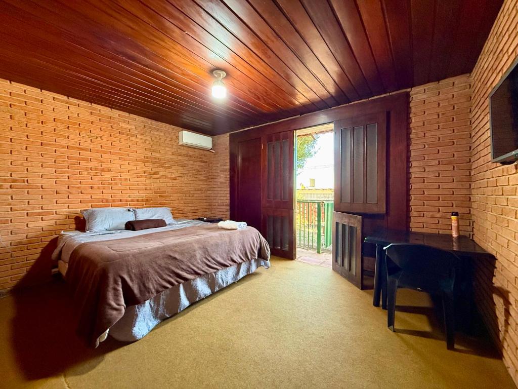 a bedroom with a bed in a brick wall at Suíte com Ar condicionado no Centro de Botucatu in Botucatu