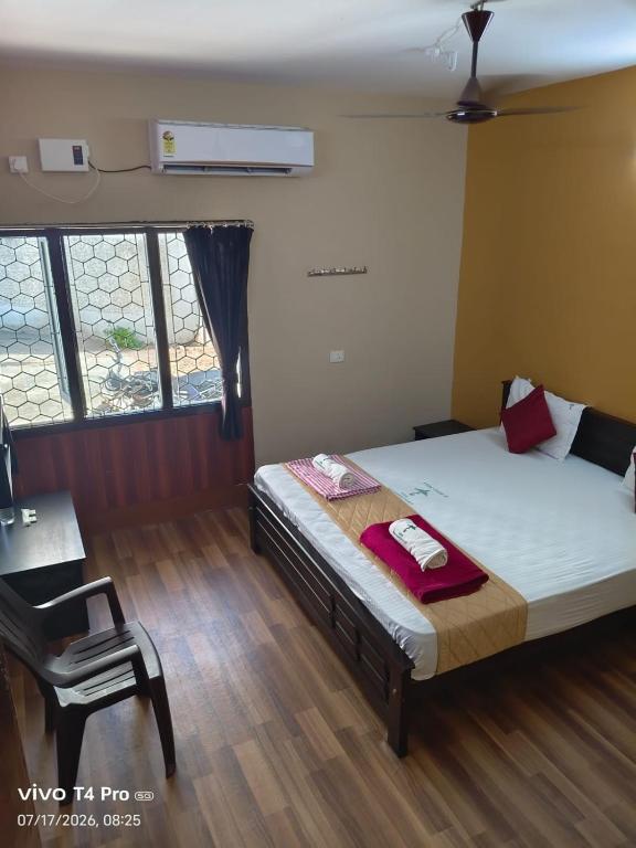 a bedroom with a bed and a chair and windows at Hotel Tamilnadu-Unit 2 in Rāmeswaram