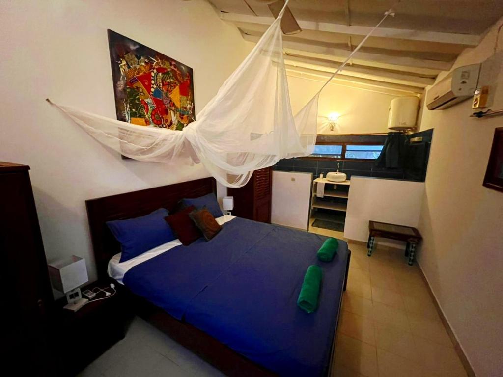 a bedroom with a blue bed with a mosquito net at Beach House in Saly Portudal