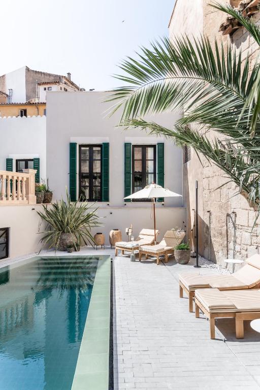 a pool with chaise lounge chairs and a house at Concepcio by Nobis, Palma, a Member of Design Hotels in Palma de Mallorca