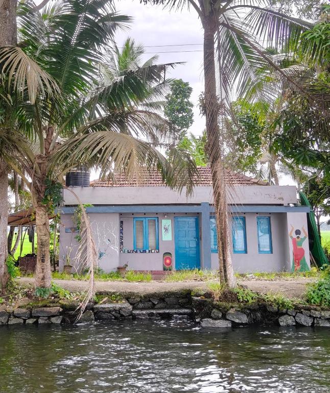 a house with palm trees in front of a body of water at Lakecampers for foreign travellers in Alleppey