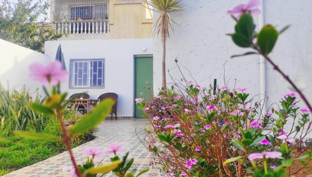 a white house with a green door and some flowers at Petit villa centre harhoura Près de la plage in Temara