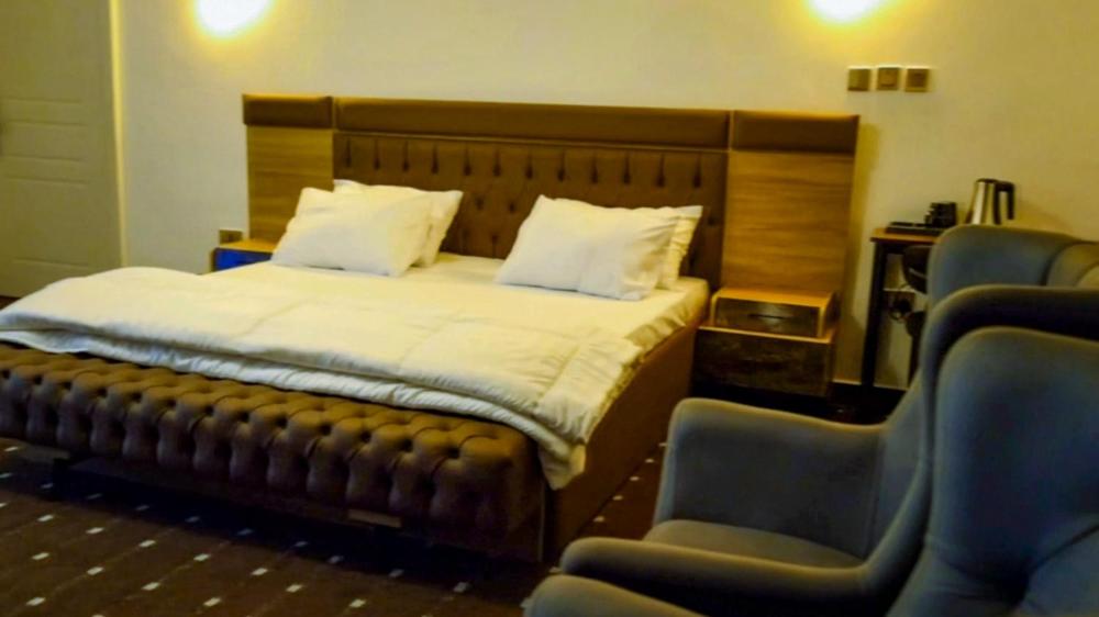 a bedroom with a bed and two blue chairs at Peev Apartments in Abuja
