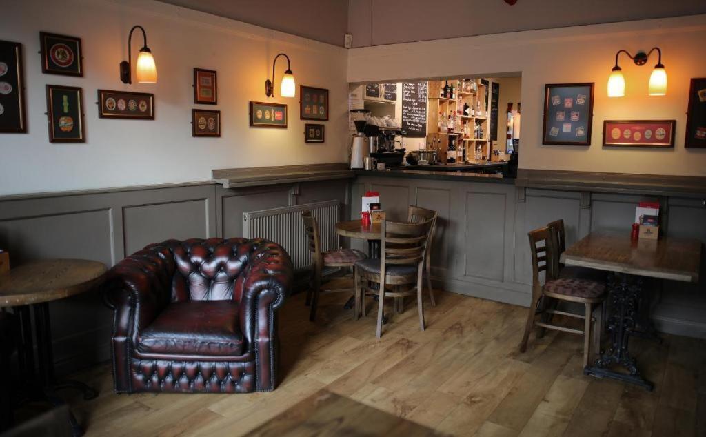 a bar with a leather chair and a table and chairs at The Horse & Farrier in Otley
