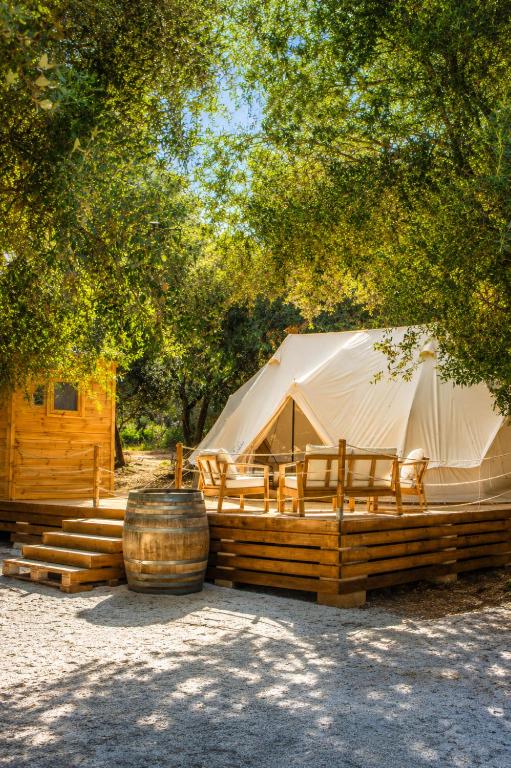 a tent with chairs and a barrel under a tree at Glamping Masseria Cuturi in Manduria