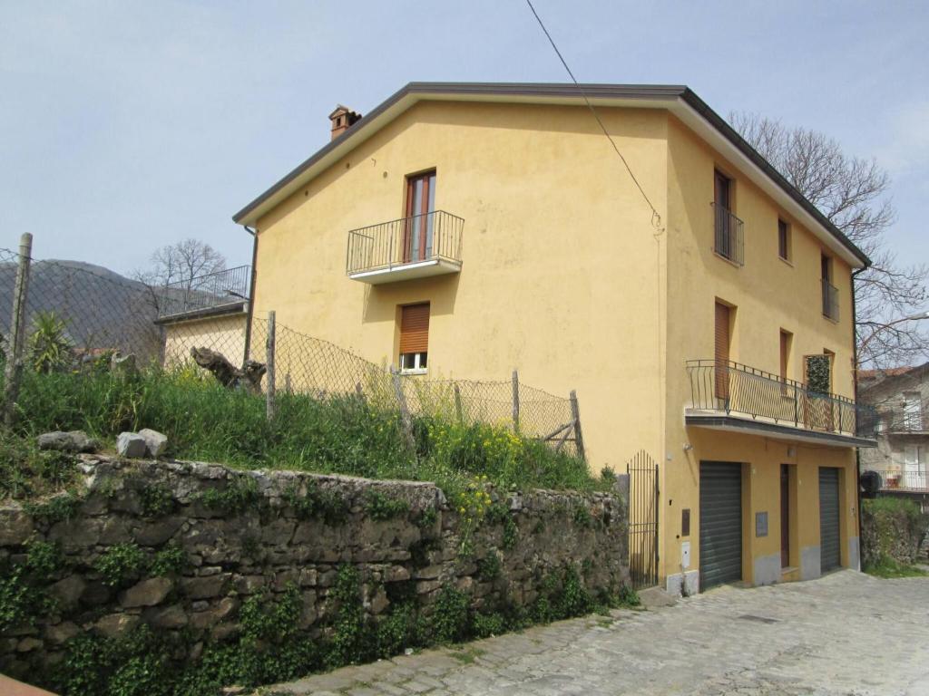 a large yellow house with a stone wall at Biagio and Marias house in Trecchina