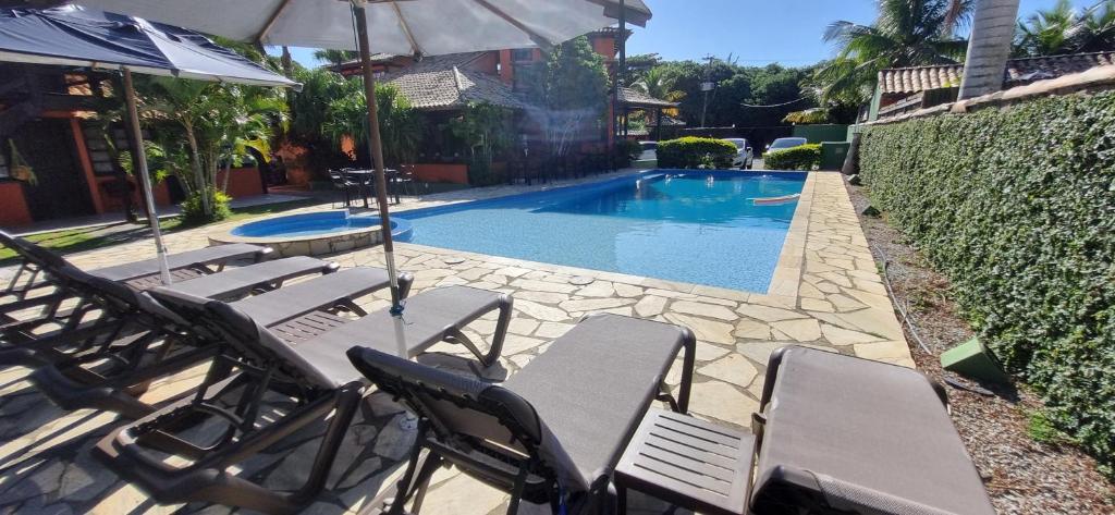 a group of chairs and an umbrella next to a pool at Pousada Da Ferradura in Búzios