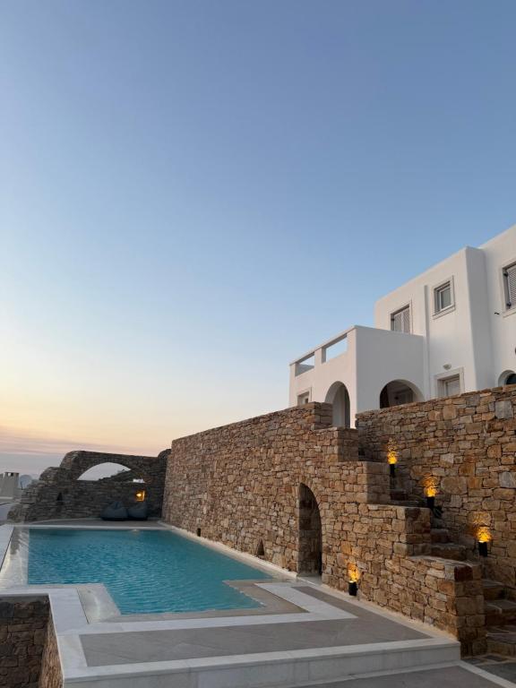 a villa with a swimming pool next to a stone wall at Anemoessa in Naxos Chora