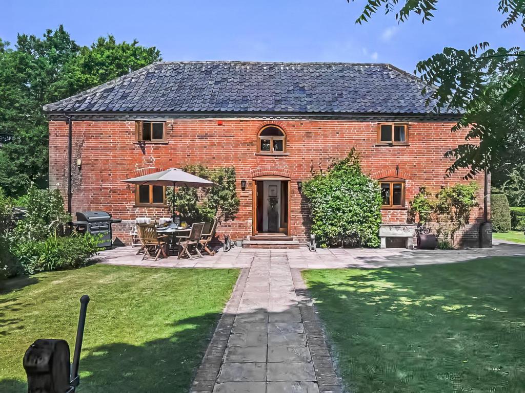 a brick house with a table and chairs in a yard at The Granary - Uk52147 in Brundall